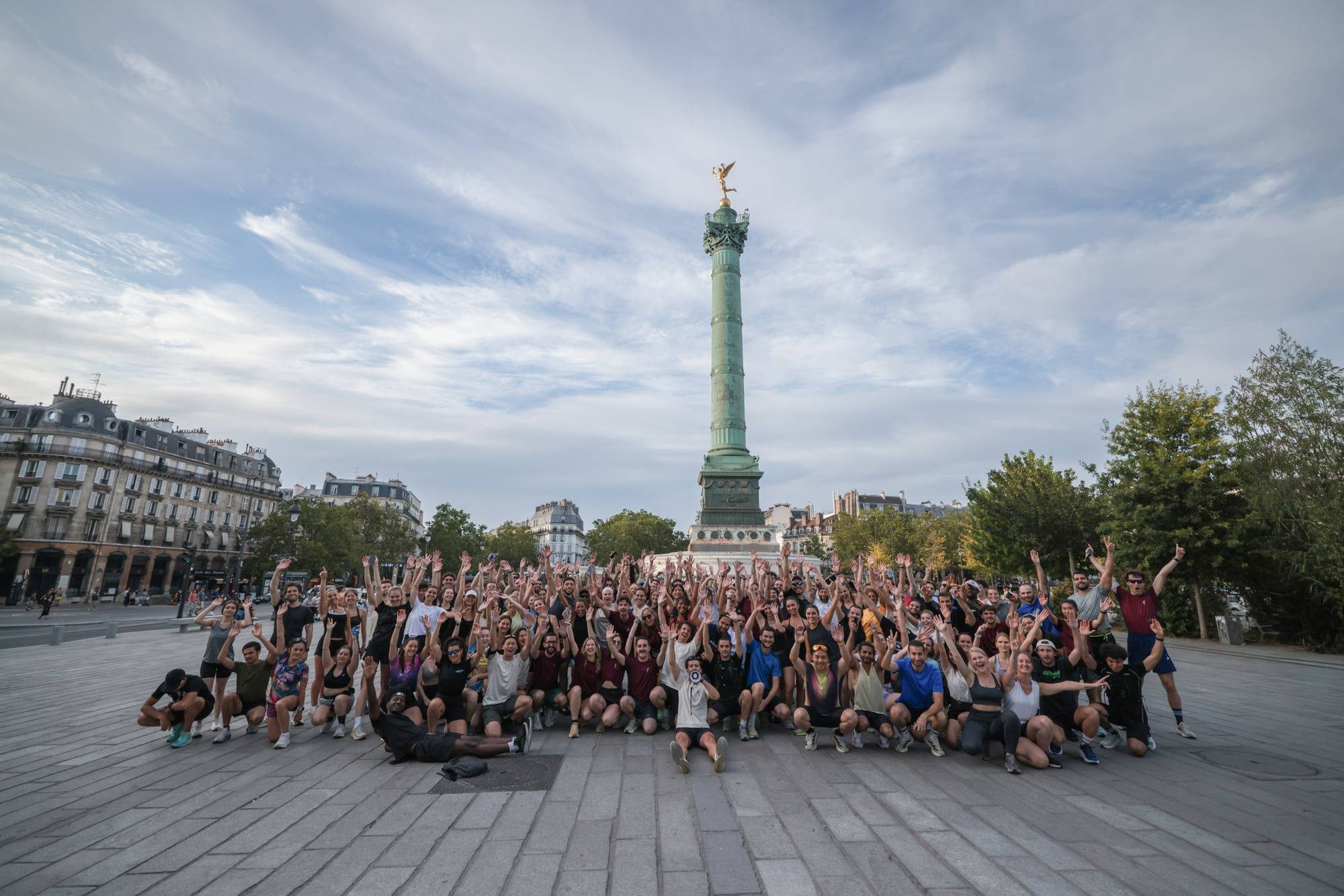 Photo de groupe du Paris 11 Running Club place de la Bastille, une centaine de coureurs bras levés